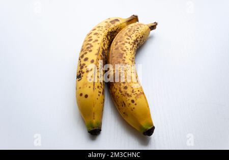 Schließen Sie zwei gelbe Sommersprossen in vertikaler Form über einem weißen Holztisch. Stockfoto