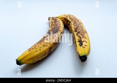 Schließen Sie zwei gelbe Sommersprossen in vertikaler Form über einem weißen Holztisch. Stockfoto