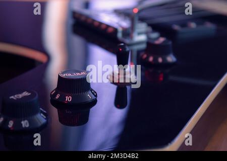 Schließen Sie sich einer elektrischen Gitarre mit volumen und Tonreglern mit roten Lichtern an. Instrumente und Musikkonzept Stockfoto