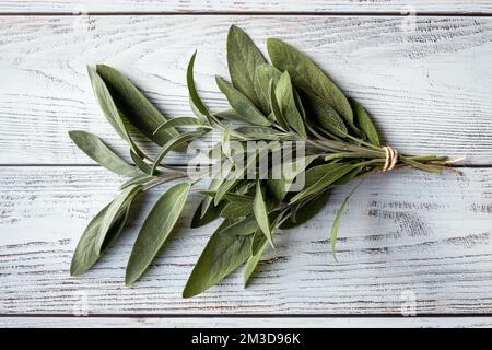 Salbeiblätter auf Holztisch, frisch gepflückter Gartensalbei, natürliches Licht Stockfoto