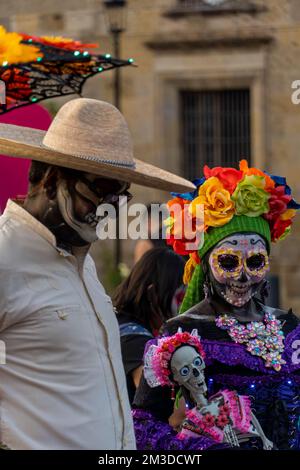 Ein Mann, der als Charro für den Tag der Toten verkleidet ist, neben einer Frau, die als catrina verkleidet ist. Stockfoto