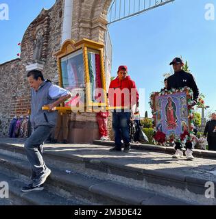 Cholula, Puebla, USA. 10.. Dezember 2022. Die Ehrungen an Maria (Unsere Lieben Frau von) Guadalupe werden von der Kirche San Francisco Acatepec in Cholula, Mexiko, nahe Puebla, nach ihrer Segnung am Samstag, den 10. Dezember 2022 getragen. Tausende von Pilgern begeben sich jedes Jahr zur Basilika unserer Lieben Frau von Guadalupe in Mexiko-Stadt, um am 12. Dezember eine Feier zu feiern. (Kreditbild: © Mark Hertzberg/ZUMA Press Wire) Stockfoto