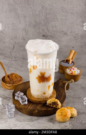 Boba- oder Tapiokapperlen ist taiwan Bubble Milk Tea in Plastikbecher mit Ananasmarmelade auf texturiertem Hintergrund, Sommererfrischung. Stockfoto