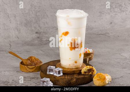 Boba- oder Tapiokapperlen ist taiwan Bubble Milk Tea in Plastikbecher mit Ananasmarmelade auf texturiertem Hintergrund, Sommererfrischung. Stockfoto