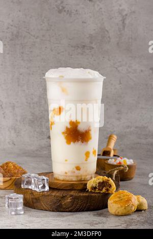 Boba- oder Tapiokapperlen ist taiwan Bubble Milk Tea in Plastikbecher mit Ananasmarmelade auf texturiertem Hintergrund, Sommererfrischung. Stockfoto