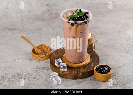 Boba- oder Tapiokapperlen ist taiwan Seifenmilchtee in Plastikbecher mit Schokoladen-Minze-Aroma auf Texturhintergrund, Sommererfrischung. Stockfoto