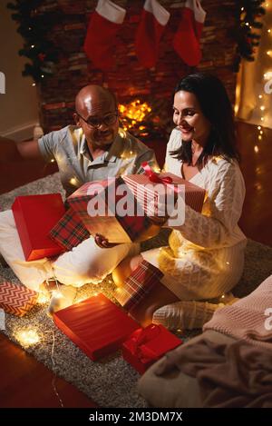 Frohes, interrassisches Weißes, afroamerikanisches, schwarzes Paar, Frau und Mann, die Geschenke eröffnen, Spaß haben, Neujahrsweihnachtsfest feiern. Geschenkgeschenk Stockfoto