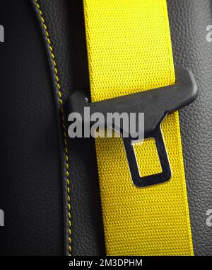 Moderner Innenraum aus schwarzem Leder für Rennwagen. Ein Teil der Details der Autositze aus gelbem Leder. Nahaufnahme des Sicherheitsgurts Stockfoto