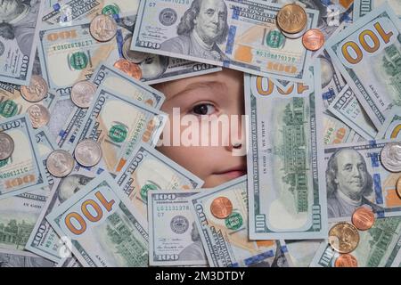 Geld und Bankwesen. Geld gewinnt, viel Glück. Lustiges Kind mit lustigem Gesicht und Geld. Ein Kind, das mit schockierten Augen aus Dollarscheinen guckt. Geld Stockfoto