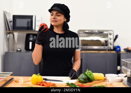 Eine Mexikanerin, die lacht, während sie Tacos in der Küche kocht Stockfoto