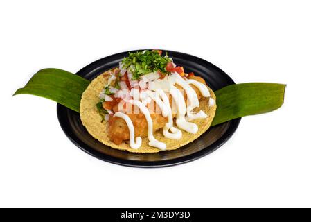 Taco condesa mit gebratenem Fisch auf schwarzem Teller isoliert auf weißem Hintergrund Stockfoto