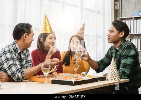 Eine Gruppe verschiedener asiatischer Freunde versammelt sich, um Weihnachten mit Champagner und Pizza zu Hause zu feiern. Freude an einer Feiertagsparty mit Freunden oder Kollegen Stockfoto