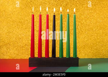 Afroamerikanisches Kwanzaa-Urlaubskonzept mit traditionell angeleuchteten Kerzen auf symbolischem Hintergrund Stockfoto