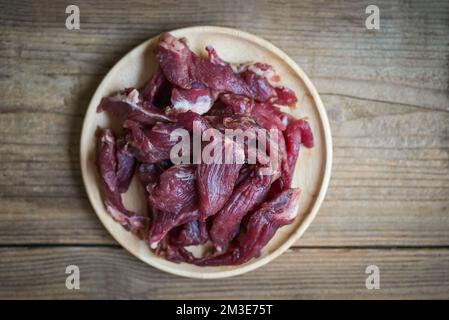 Rindfleisch Jerky auf Holzteller, rohes getrocknetes Fleisch zum Kochen, trockenes Fleisch in Thailand Essen - Draufsicht Stockfoto
