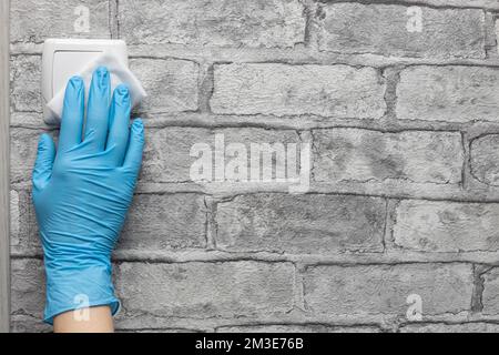 Der Mann wischt den Schalter mit einer Serviette ab. Hausdesinfektion. Hausreinigung. Nahreinigung. Stockfoto