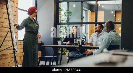 Muslimischer Teamleiter hält während einer Bürobesprechung eine Präsentation. Kreative Geschäftsfrau, die ihre Ideen mit Kollegen teilt. Gruppe von Geschäftsleuten w Stockfoto