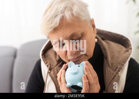 Geldverwaltungskonzept. Eine ältere Frau hält ein Sparschwein Stockfoto