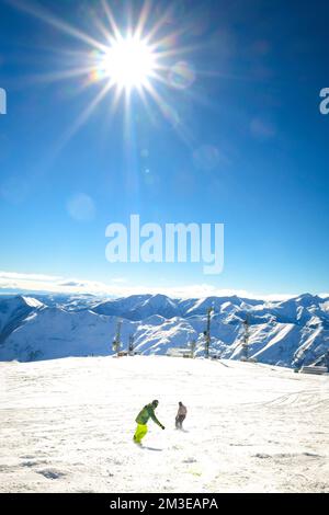 Zwei Freunde Snowboarder mit Blick auf den Rückblick auf den Urlaub im Skigebiet haben Spaß zusammen mit dem Hintergrund der blauen Berge Stockfoto