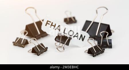 Geschäfts- und Finanzkonzept. Auf einem weißen Tisch befinden sich Büroklammern, in einem Clip ist Papier mit der Aufschrift "FHA LOAN" Stockfoto