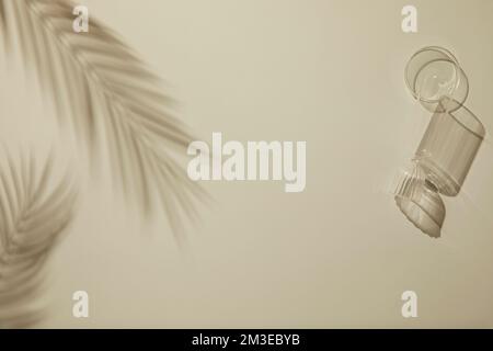 Einfacher, minimaler und entsättigter Hintergrund mit Palmenblättern und gemusterten Glasflaschen mit Kopierbereich in der Mitte Stockfoto