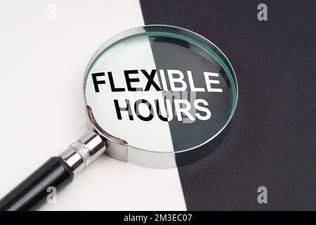 Geschäftskonzept. Auf der Oberfläche, die halb schwarz und weiß ist, liegt eine Lupe, in der geschrieben ist: FLEXIBLE STUNDEN Stockfoto