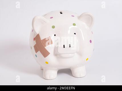 Sparschwein mit klebrigen Pflastern, isoliert auf weiß. Stockfoto