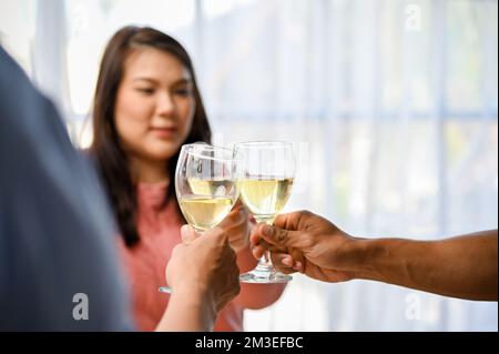 Eine Gruppe von Freunden, die auf der Party anstoßen und Wein trinken. Ein glücklicher Moment, der den Sieg feiert. Nahaufnahme Stockfoto