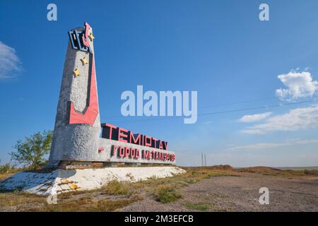 Das große Schild am Highway zeigt eine abstrakte Grafik eines Eimers, der geschmolzenes Eisenerz für die Stahlherstellung, die wichtigste Industrie der Stadt, ausgießt. In Temi Stockfoto