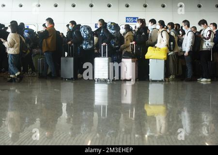 HANGZHOU, CHINA - 15. DEZEMBER 2022 - Eine große Anzahl von Passagieren mit Masken wartet in der Warterhalle des Ostbahnhofs Hangzhou in Hangzhou Stockfoto