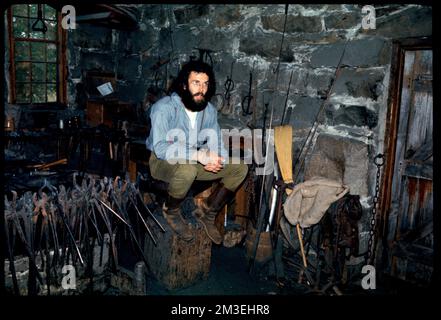 Mann sitzt in der Schmiede, Old Sturbridge Village, Sturbridge, Massachusetts, Blacksmiths, Schmiedegeschäfte, historische Nachstellungen, historische Stätten, Old Sturbridge Village. Edmund L. Mitchell Kollektion Stockfoto