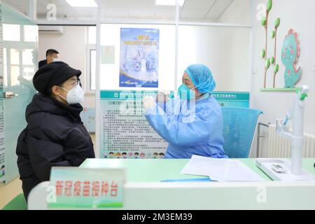 QINGDAO, CHINA - 15. DEZEMBER 2022 - Ein Mitarbeiter erläutert die Vorsichtsmaßnahmen für die Inhalation von COVID-19-Impfungen in einem gemeindenahen Gesundheitszentrum Stockfoto