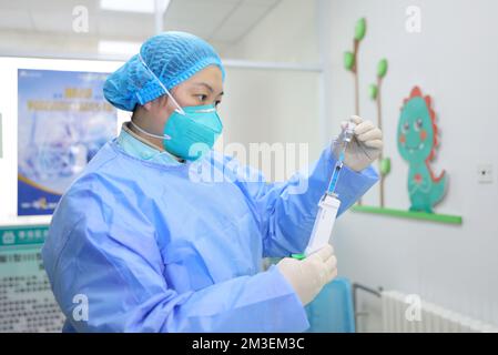 QINGDAO, CHINA - 15. DEZEMBER 2022 - Ein Mitarbeiter nimmt Flüssigkeit für die Inhalation des COVID-19-Impfstoffes in einem Gesundheitszentrum in Qingda auf Stockfoto