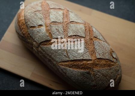 Frisch gebackenes Brot auf dunkelgrauem Küchentisch und Holzschreibtisch, Draufsicht Stockfoto