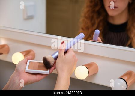 Unbekannte junge Ballerina, die sich vor dem Spiegel schminkt. Stockfoto