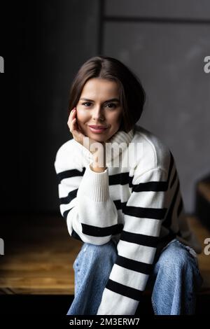 Eine junge Frau, die sich entspannt auf der Treppe in ihrem modernen Apartment aufhält Stockfoto