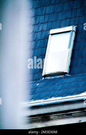 Ein vertikales Bild eines gefliesten Dachs mit einem Fenster Stockfoto