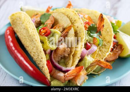 Mexikanische Tacos mit Garnelen, Guacamole und Gemüse auf einem Holztisch Stockfoto