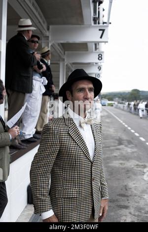 Enthusiasten ziehen sich gern in antiken Kleidern an, um die Atmosphäre des Goodwood Revival in Sussex, England, zu genießen. Stockfoto