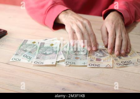 Zählen polnischer Zloty-Banknoten mit Taschenrechner auf dem Tisch und farbigem Hintergrund Stockfoto