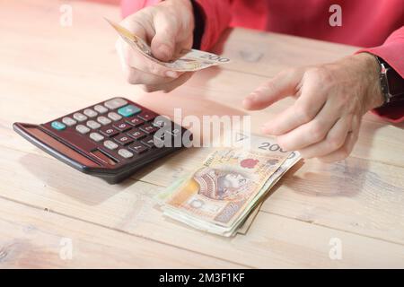 Zählen polnischer Zloty-Banknoten mit Taschenrechner auf dem Tisch und farbigem Hintergrund Stockfoto