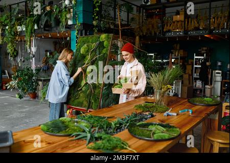 Zwei Designer arbeiten an Blumencollagen im Floristen-Shop Stockfoto