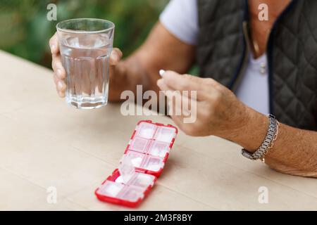 Seniorin nimmt Pillen aus der Box. Gesundheitsvorsorge und Alterskonzept mit Medikamenten. Medikamente auf dem Tisch Stockfoto