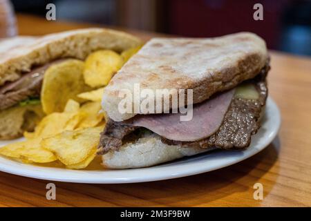 Bolo do Caco ist ein rundes Madeiranisches Fladenbrot, das wie ein Kuchen geformt und daher Bolo genannt wird. Das Brot wird mit Steak, Käse und Schinken serviert. Stockfoto