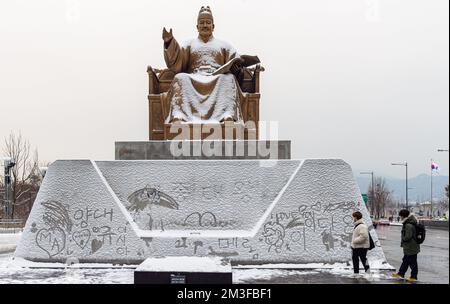 Besucher spazieren durch die Statue von Sejong dem Großen mit weißem Schnee und Hangeul Graffiti im Schnee. Die Statue von Sejong dem Großen befindet sich am Gwanghwamun Plaza im Zentrum von Seoul. Am 15. Dezember soll die südkoreanische Hauptstadt und die zentralen Regionen von starkem Schnee heimgesucht werden, und in einigen Teilen der Provinzen Gyeonggi, Gangwon und North Chungcheong werden voraussichtlich Schneefälle von mehr als 10 Zentimetern zu sehen sein, so die Wetterbehörde. Die Provinzen North Chungcheong und South Chungcheong werden voraussichtlich Schneefälle zwischen 3 und 30 km erwarten Stockfoto