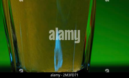 Grüner Hintergrund . Clip. Ein heller Hintergrund, auf dem gelbe kohlensäurehaltige Limonade in Gläser gegossen wird. Hochwertige 4K-Aufnahmen Stockfoto
