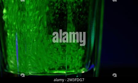 Erfrischendes kohlensäurehaltiges Getränk in transparentem Glas, isoliert auf einem farbenfrohen Wandhintergrund. Clip-Material. Kühles Cola-Soda-Getränk an der Bar Stockfoto