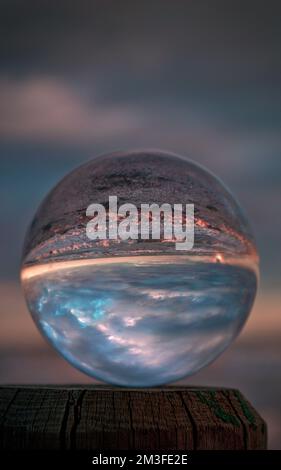 Transparente Linsenkugel im Hintergrund einer Meereslandschaft. Trasparent glänzende Linsenkugel. Stockfoto