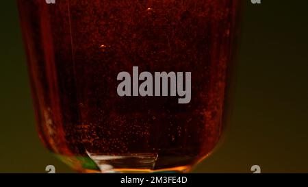 Nahaufnahme eines alkoholischen Getränks in durchsichtigem Glas. Clip. Alkoholgetränk isoliert auf farbenfrohem Wandhintergrund Stockfoto