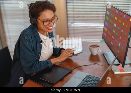Grafikdesignerin verwendet Smartphone während des Arbeitstages im Home Office Stockfoto