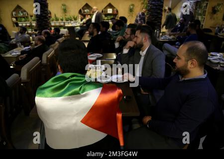 Teheran, Teheran, Iran. 14.. Dezember 2022. Ein iranischer Fan, der eine palästinensische Flagge trug, während er das Nakhlestan Café in der Innenstadt von Teheran besuchte, weil er das Halbfinale der FIFA-Weltmeisterschaft Katar 2022 zwischen Frankreich und Marokko am 14. Dezember 2022 auf der Leinwand gesehen hat. Fans aus dem Iran, dem Libanon, dem Jemen, Syrien und Palästina versammeln sich im Nakhlestan Cafe, das vom Owj, der Arts and Media Organization des Islamic Revolutionary Guard Corps (IRGS), betrieben wird und sich im Besitz der Organisation für Kunst und Medien befindet, um die marokkanische Nationalmannschaft zu unterstützen. Nach dem Sieg gegen Portugal in Katar am 10.. Dezember trugen die Marokkaner palästinensische Flaggen, um ihre Unterstützung zu zeigen Stockfoto